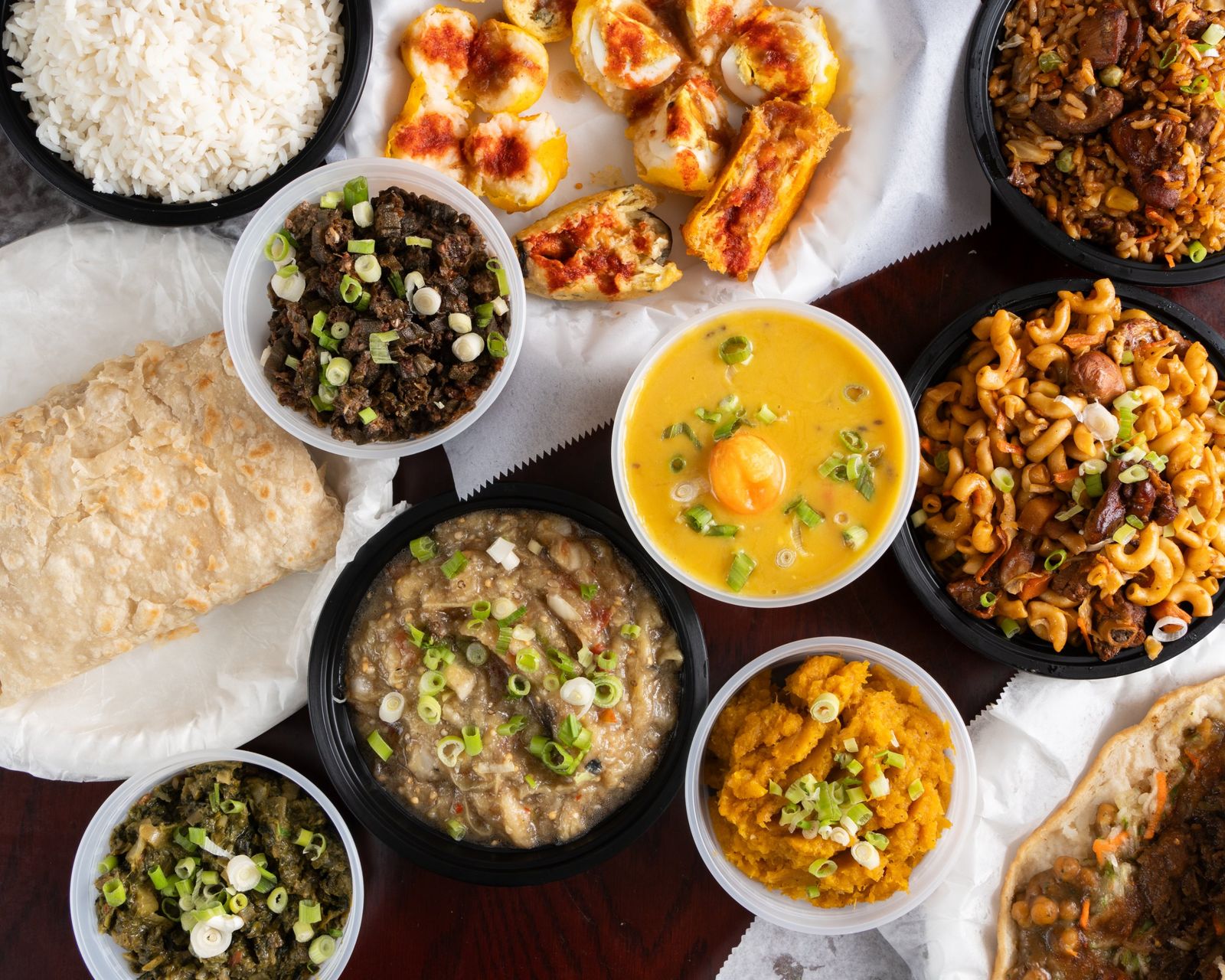 A spread of Guyanese dishes from Julie's: roti, dhal, pumpkin, calaloo, bora, cook-up rice and doubles
